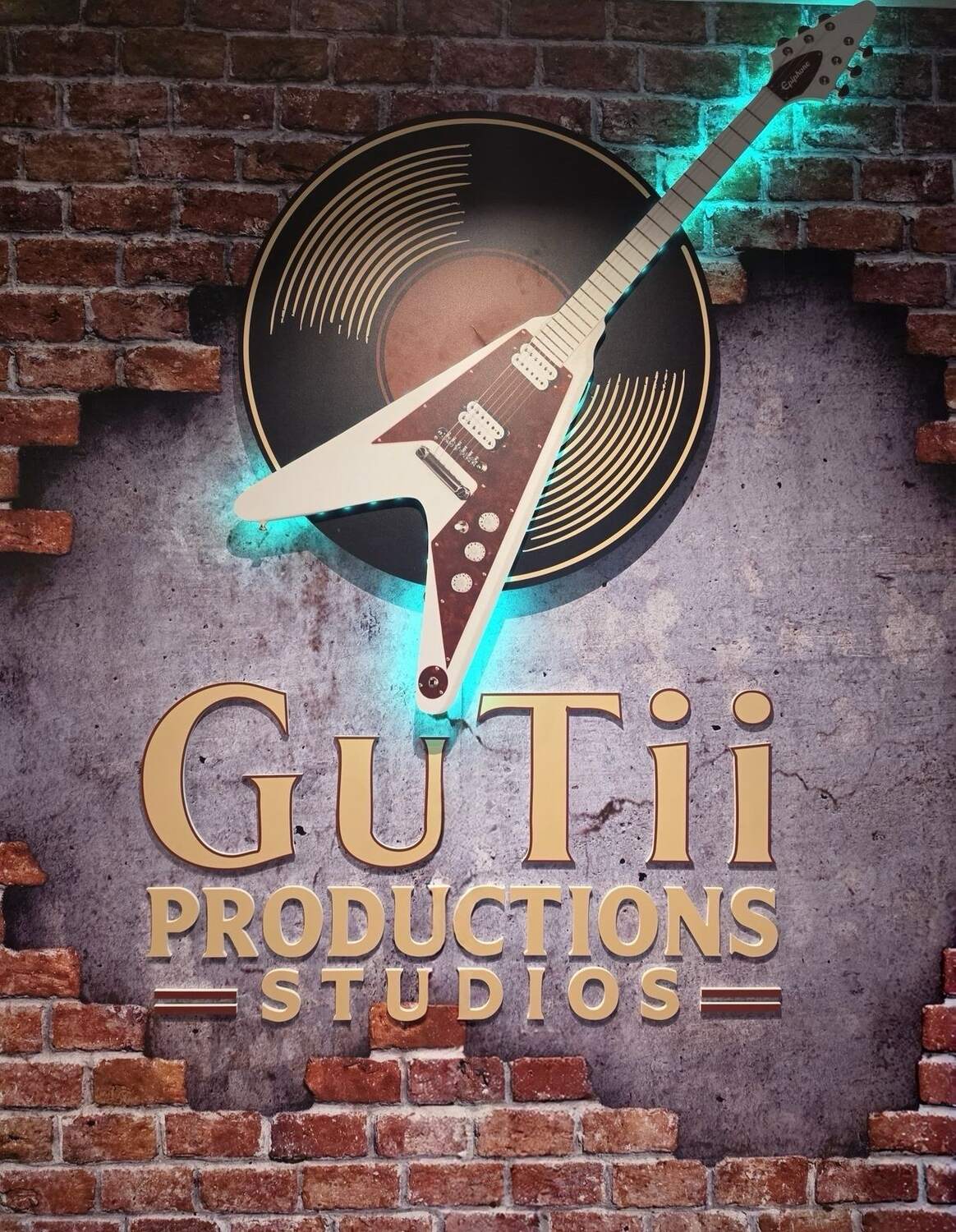 Gutii Productions Studios signature brick and neon studio wall